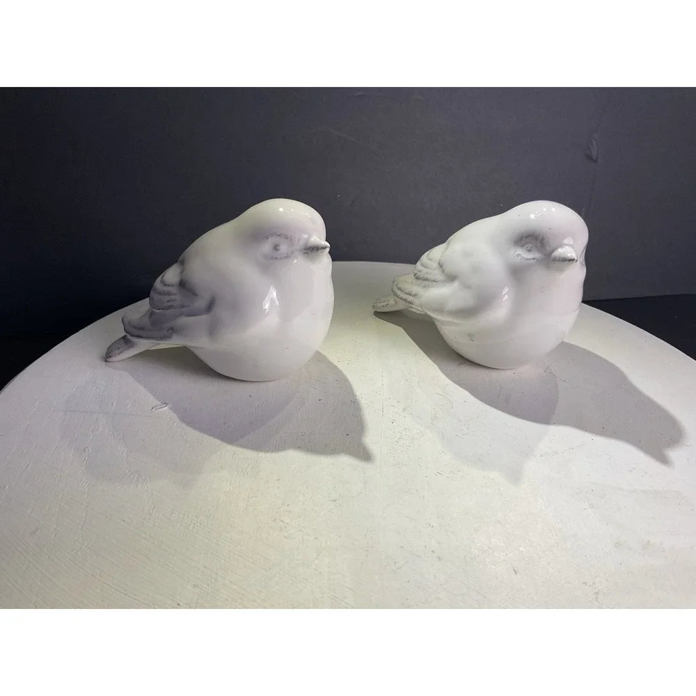 Two little bird figurines with some coloring on the feathers